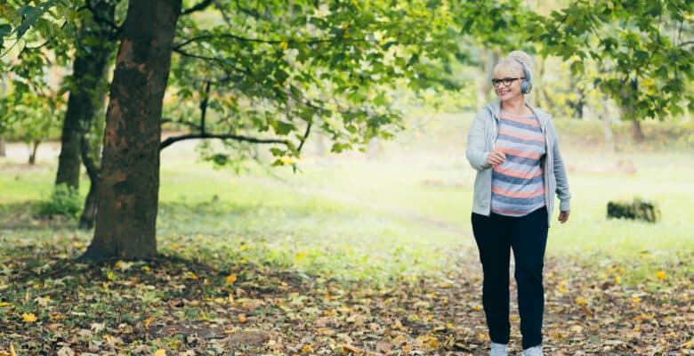 Beautiful woman, senior, running in headphones, walking in the park, playing sports
